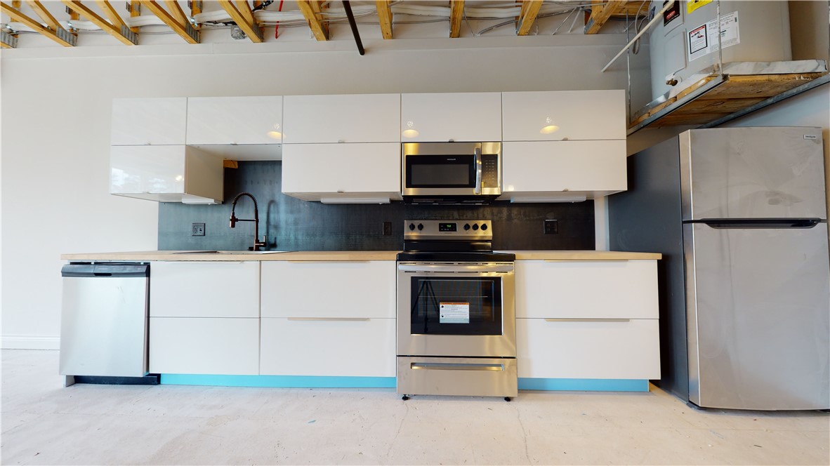 305 West 27th Street, Unit 228 Bryan, TX 77803 - Photo 4 of 17 a kitchen with stainless steel appliances white cabinets and a refrigerator