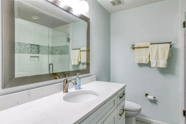 a bathroom with a granite countertop sink a toilet and mirror