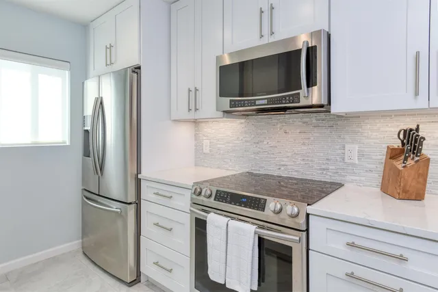 a kitchen with stainless steel appliances white cabinets and a stove top oven