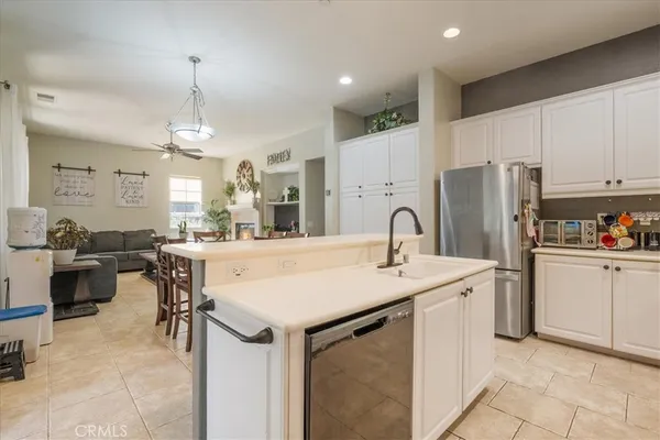 a large kitchen with kitchen island a refrigerator a sink dishwasher a dining table and chairs with wooden floor