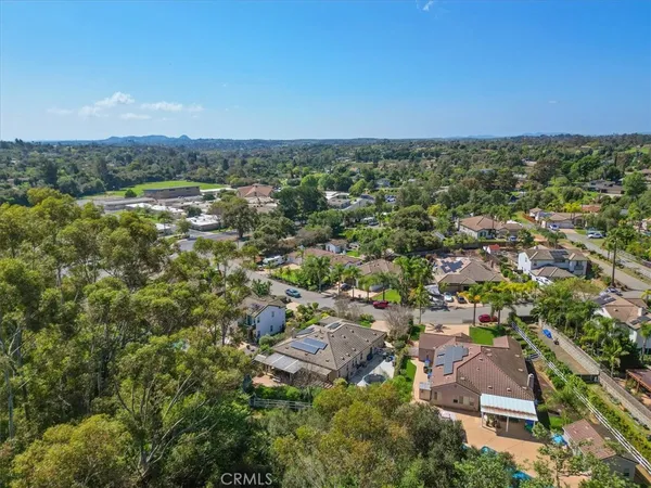 an aerial view of a residential houses with outdoor space and trees
