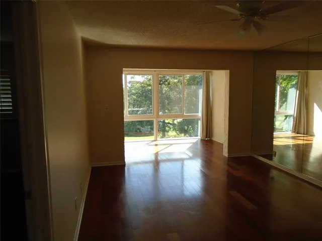 a view of empty room with wooden floor and fan
