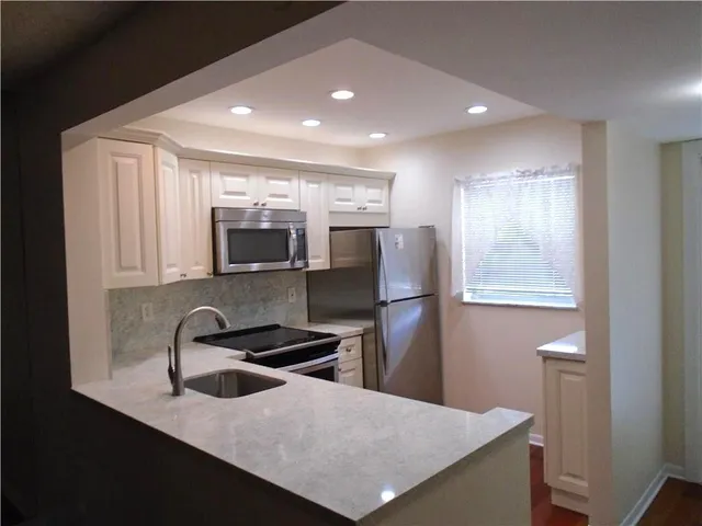 a kitchen with stainless steel appliances granite countertop a sink a refrigerator and a stove