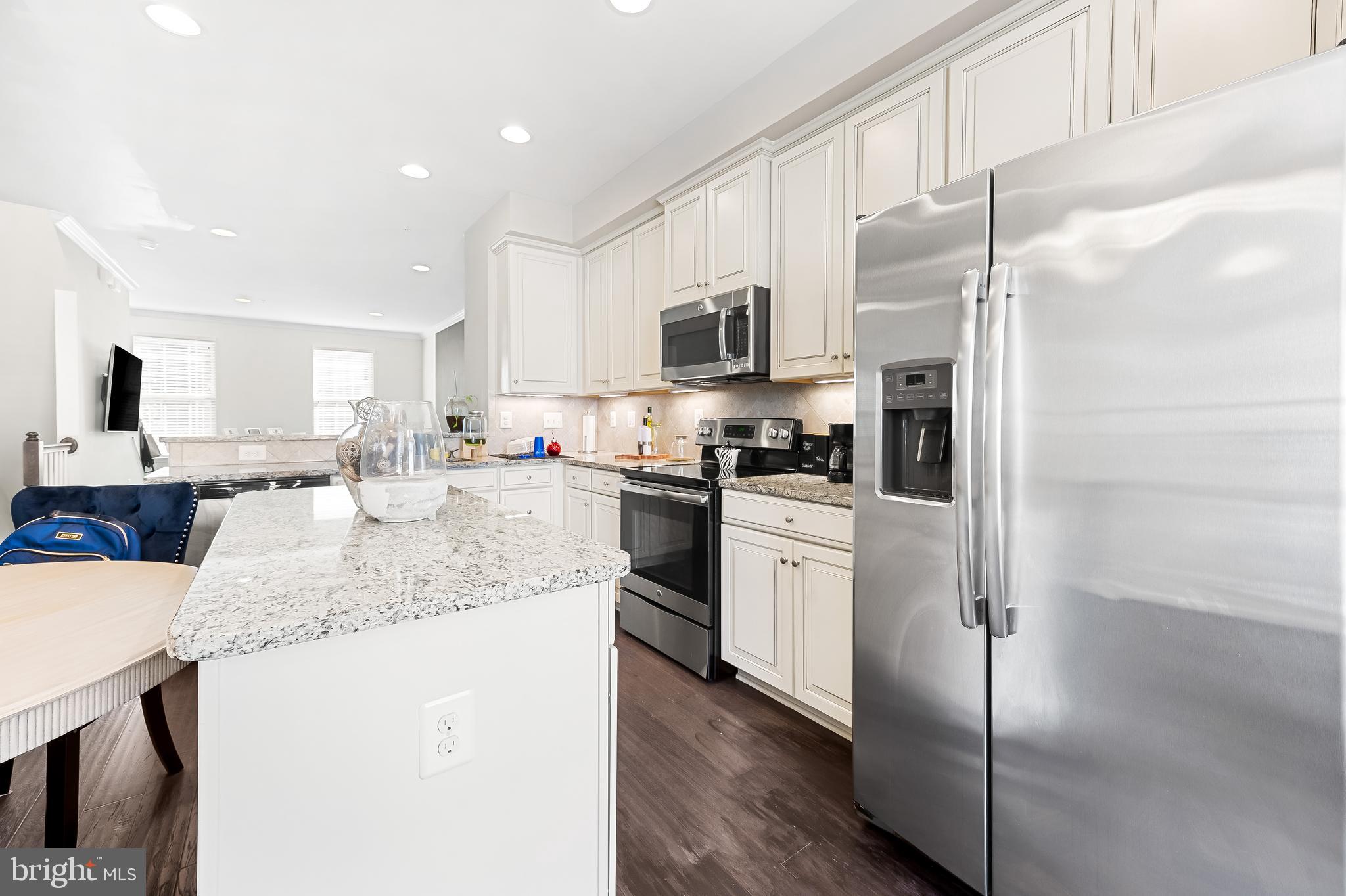 810 South Macon Street Baltimore, MD 21224 - Photo 9 of 31 a kitchen with stainless steel appliances granite countertop a refrigerator a stove a sink and white cabinets with wooden floor