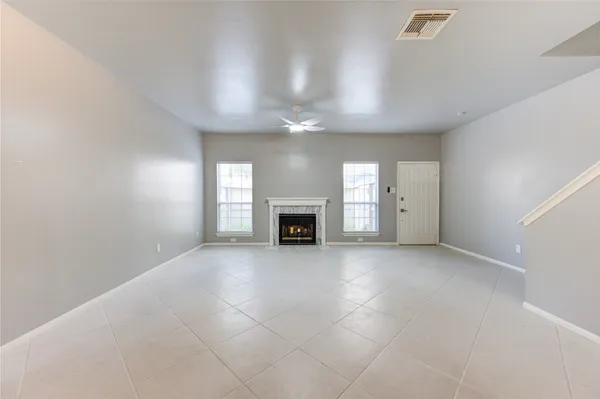 an empty room with windows and fireplace
