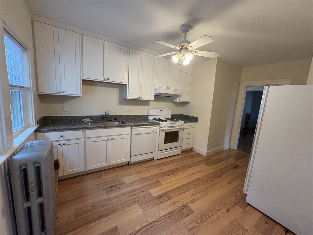 97 Warwick Road, Unit 97 Newton, MA 02465 - Photo 14 of 24 a kitchen with granite countertop a refrigerator a sink dishwasher a stove and white cabinets with wooden floor