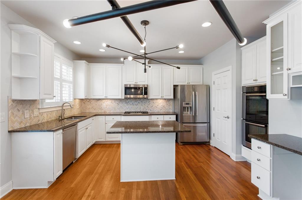 3522 Ivy Manor Road Southeast Smyrna, GA 30080 - Photo 10 of 47 a large kitchen with stainless steel appliances granite countertop a refrigerator a stove a sink and white cabinets with wooden floor