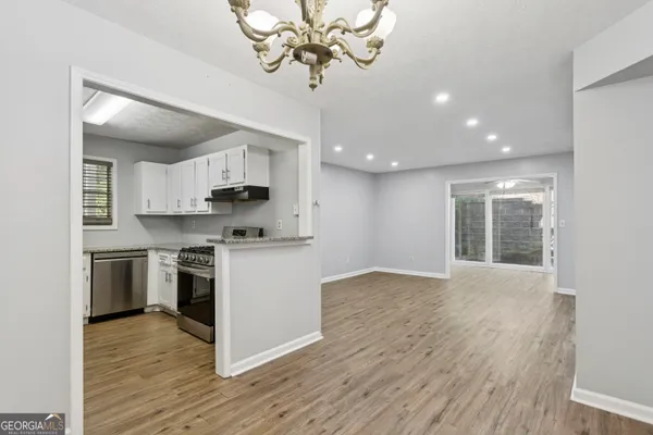 a kitchen with stainless steel appliances granite countertop a stove top oven a sink dishwasher and a refrigerator with wooden floor