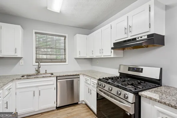 a white kitchen with sink and stove