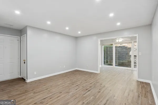 a view of an empty room with wooden floor and a window