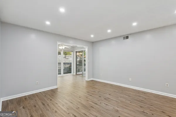 a view of an empty room with wooden floor and a window