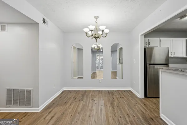 a view of a hallway with wooden floor and a kitchen