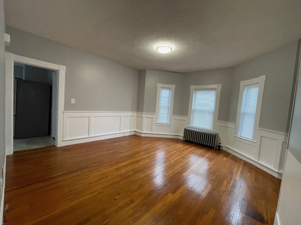 46 Lane Street, Unit 1 Lowell, MA 01851 - Photo 5 of 19 an empty room with wooden floor and windows