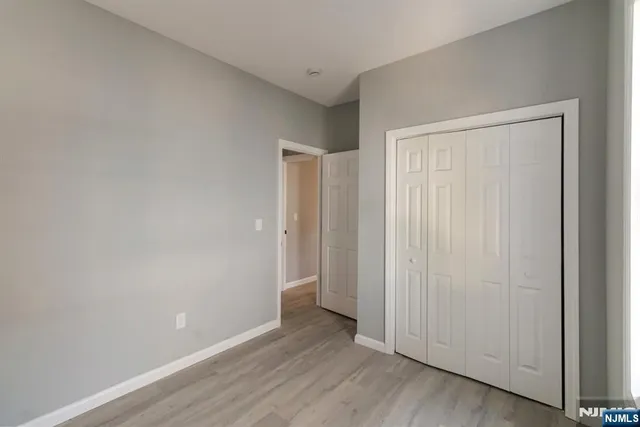 a view of an empty room with closet and wooden floor