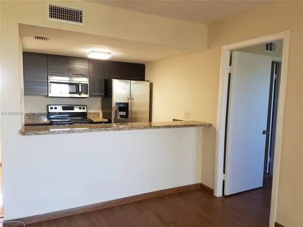a view of a kitchen with stainless steel appliances wooden floor and a large window
