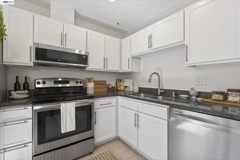 a kitchen with stainless steel appliances granite countertop white cabinets a sink a stove and dishwasher