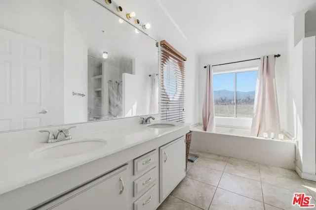 a bathroom with a sink vanity granite tub shower and a mirror