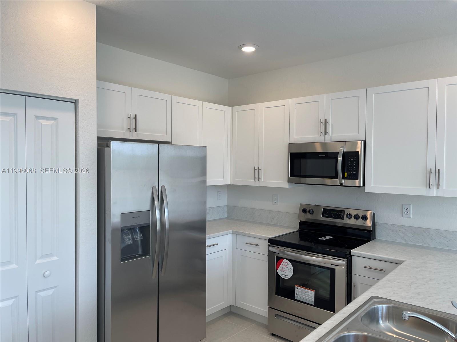 13262 Southwest 287th Terrace Homestead, FL 33033 - Photo 24 of 33 a kitchen with stainless steel appliances granite countertop a refrigerator a stove a sink and white cabinets