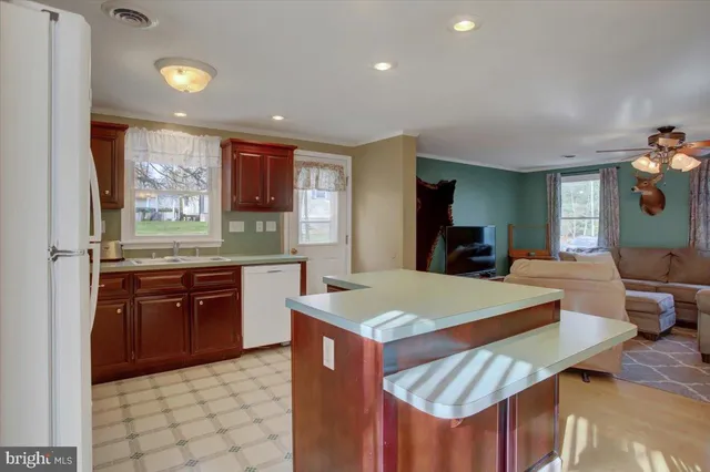 a kitchen with stainless steel appliances granite countertop a sink dishwasher and a refrigerator with wooden floor