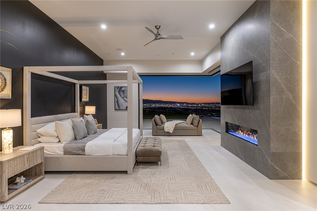 563 Grand Rim Drive Henderson, NV 89012 - Photo 46 of 70 City lights stretch endlessly from this primary bedroom, featuring a sleek fireplace and a view of the vibrant skyline.