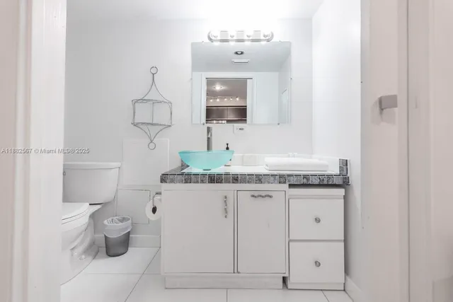 a bathroom with a granite countertop sink a toilet and a mirror