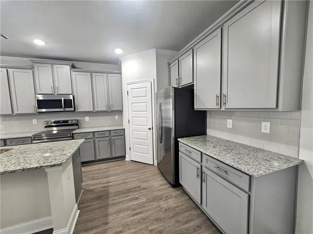 a kitchen with stainless steel appliances granite countertop a stove a sink and a refrigerator