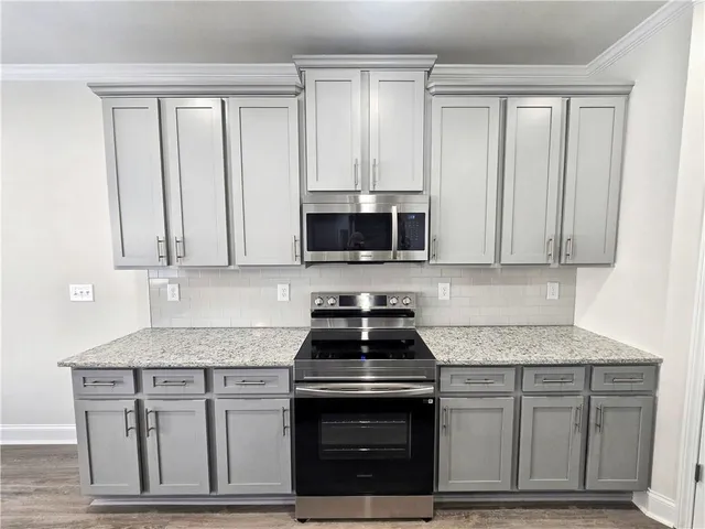 a kitchen with granite countertop white cabinets and stainless steel appliances