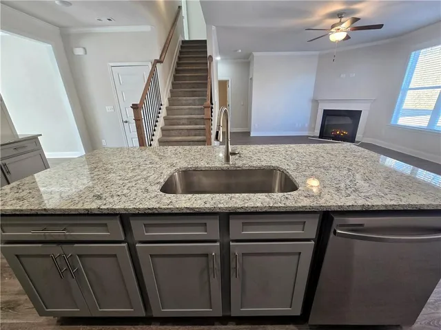 a kitchen with granite countertop a sink and a white cabinets