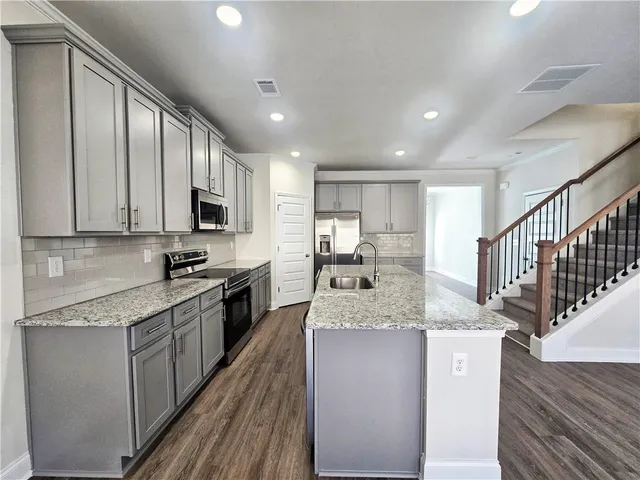 a large kitchen with stainless steel appliances granite countertop a large counter top a stove a sink and a refrigerator