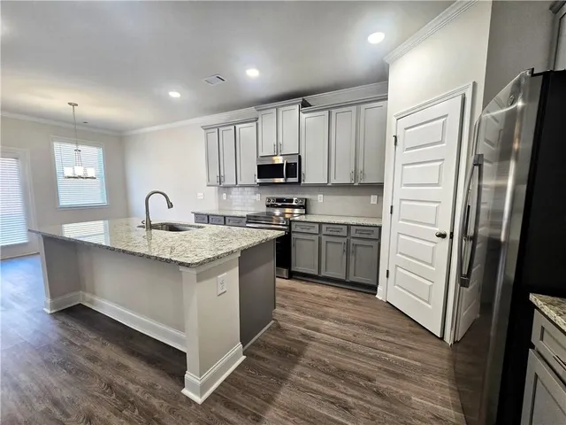 a kitchen with stainless steel appliances granite countertop a sink stove refrigerator and cabinets