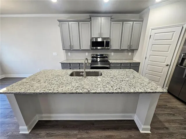 a kitchen with granite countertop a sink a stove top oven a counter space and cabinets