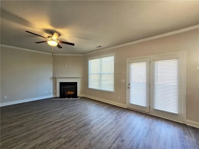 an empty room with wooden floor fireplace and windows