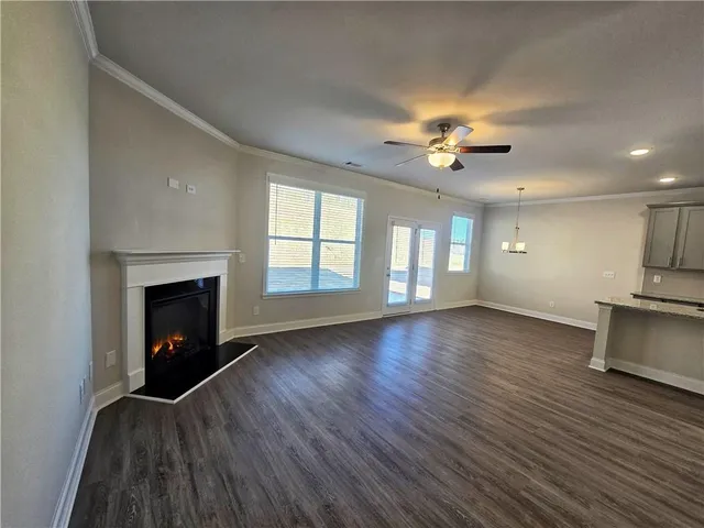 an empty room with windows fireplace and a kitchen view