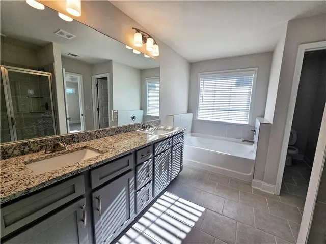 a bathroom with granite countertop double vanity and a bathtub