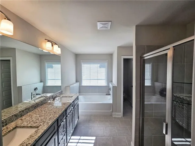 a bathroom with a granite countertop sink a mirror and a shower