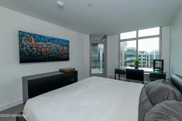 a bedroom with a bed and a flat tv screen on dresser