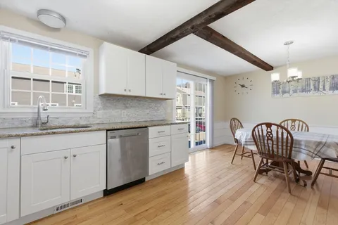 a kitchen with granite countertop white cabinets and wooden floors