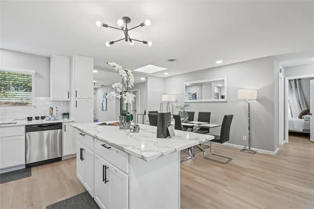 a open kitchen with stainless steel appliances kitchen island a stove a refrigerator a sink dishwasher and a fireplace with wooden floor