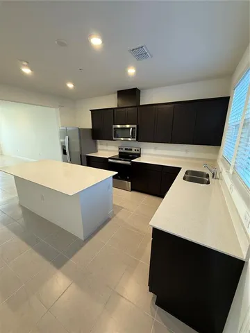 a large kitchen with kitchen island a sink dishwasher a stove and a refrigerator with wooden floor