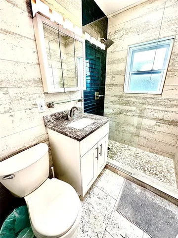 a bathroom with a granite countertop toilet sink and mirror