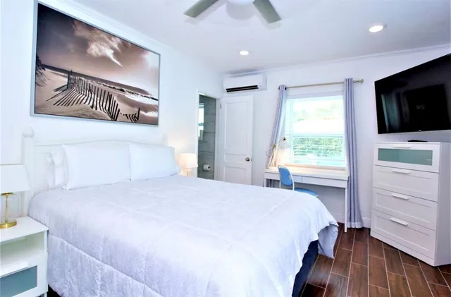 a bedroom with a large bed and a flat tv screen on dresser