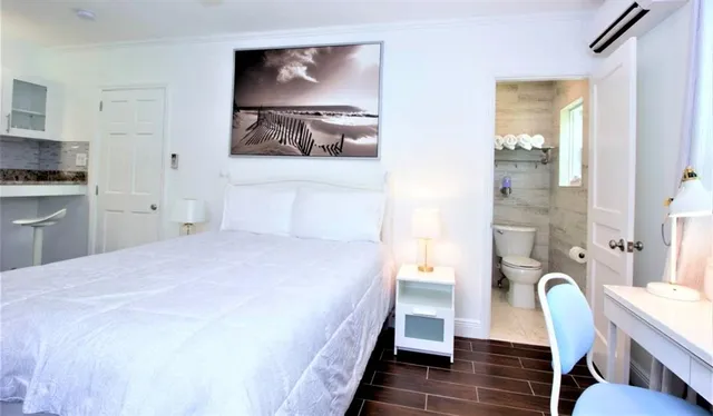 a bedroom with a bed and a chair with the wooden floor