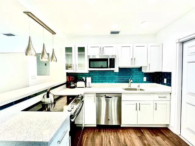 a kitchen with a sink a stove and white cabinets