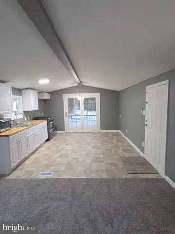 a large white kitchen with kitchen island a sink stainless steel appliances and cabinets