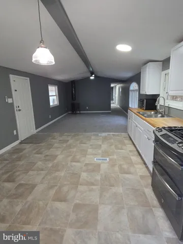 a large kitchen with kitchen island a stove a sink a counter space and a window