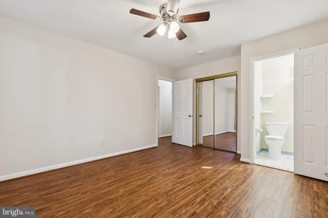 an empty room with wooden floor ceiling fan and windows