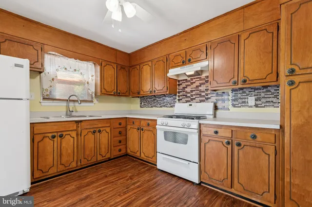 a kitchen with stainless steel appliances granite countertop wooden cabinets a sink and dishwasher with wooden floor