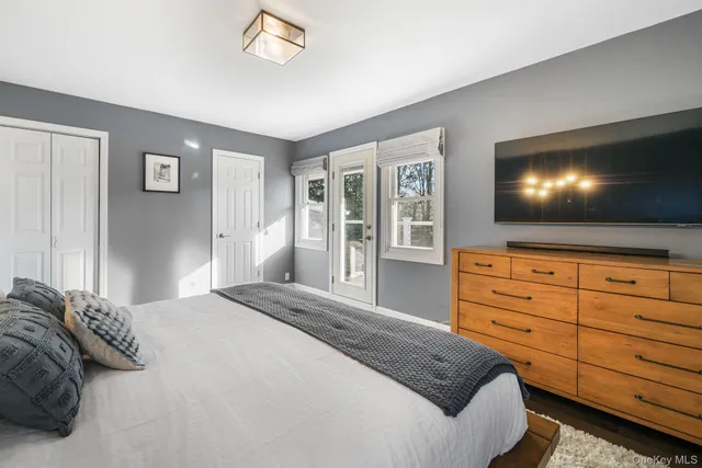 a bedroom with a large bed and a flat tv screen on dresser