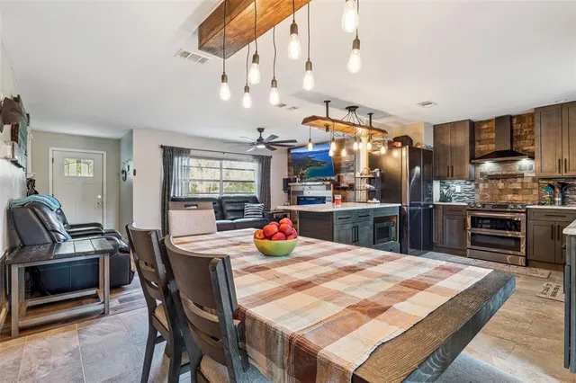 a kitchen with stainless steel appliances kitchen island granite countertop a table chairs in it and wooden floors