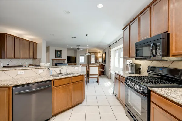 a large kitchen with stainless steel appliances granite countertop a stove top oven a sink a dining table and chairs